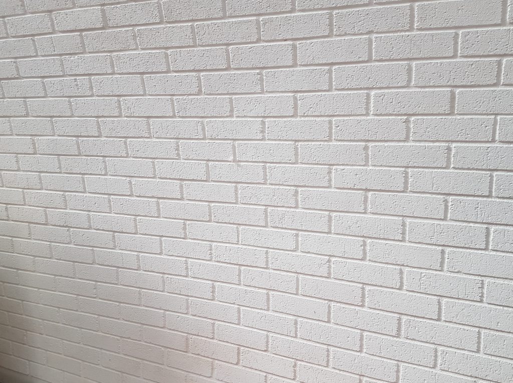 A wall covered with white brick-effect GRP cladding