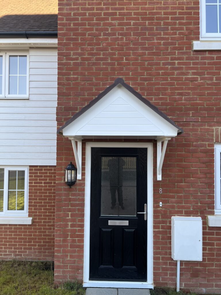 A white Worcester door canopy with a brown roof, fitted above a black door