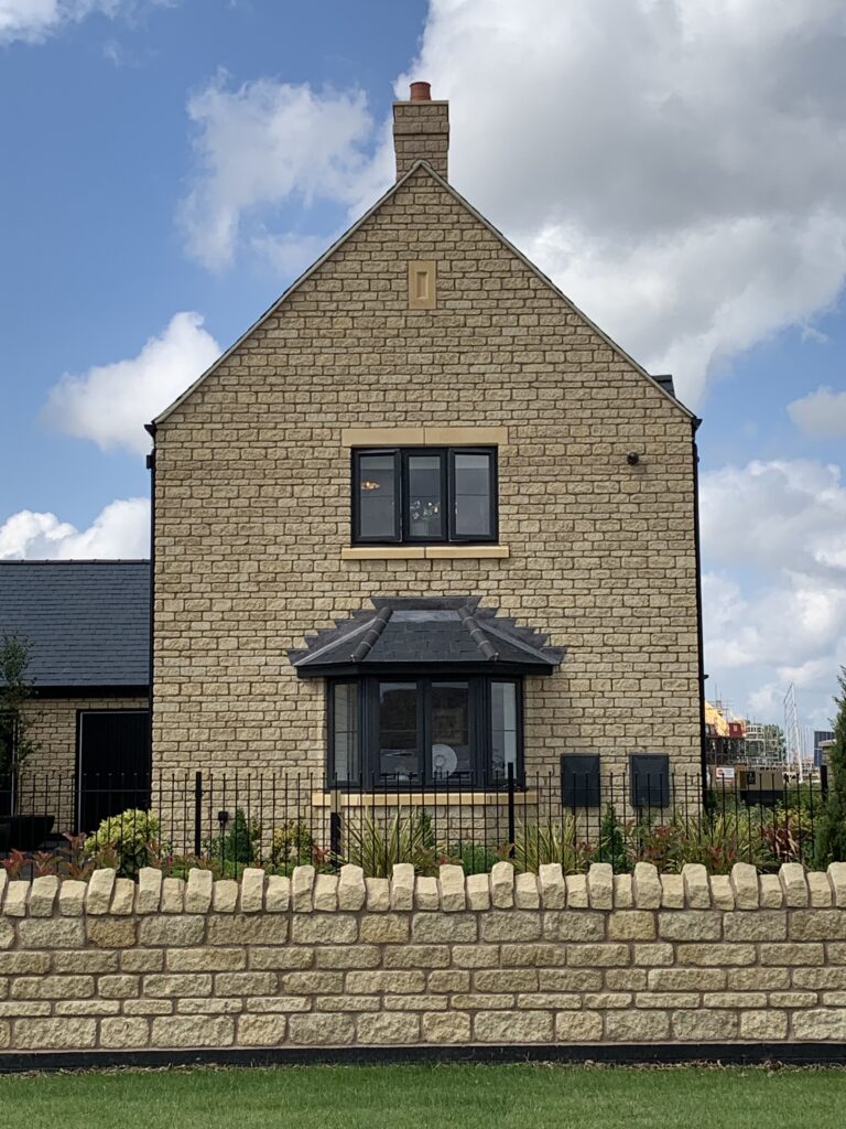 A large stone brick house with a false GRP chimney on the roof