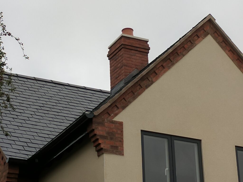 A large lightweight chimney fitted on a modern house featuring beige render and grey windows