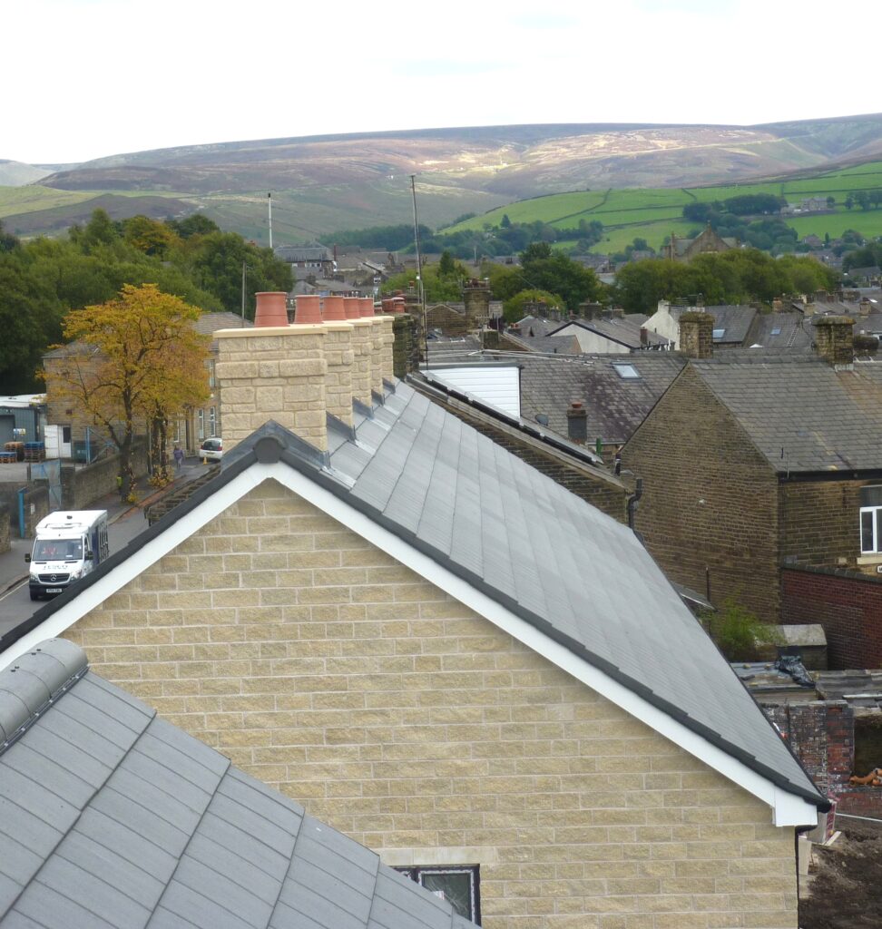 Five stone brick-effect GRP chimneys on the roof of a new row of terraced houses