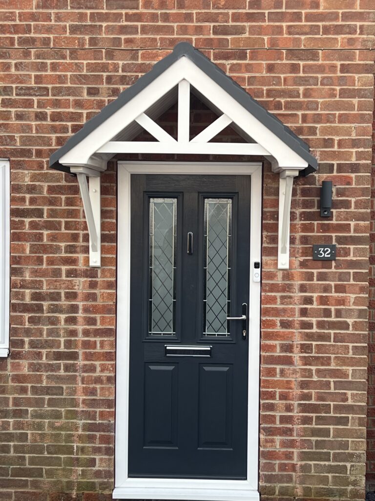 A grey front door with a duo pitch canopy above