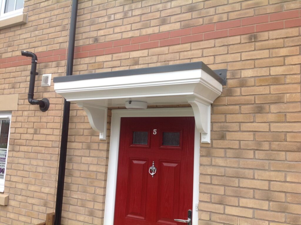 A flat canopy with a light installed above a red front door